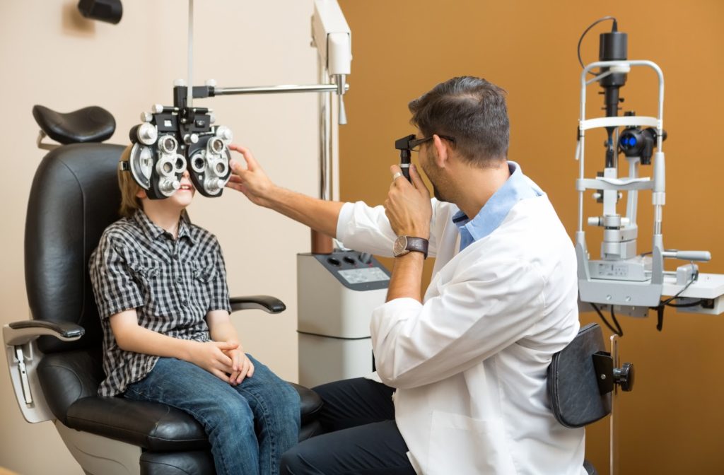 Male optometrist completing eye exam on child patient in clinic
