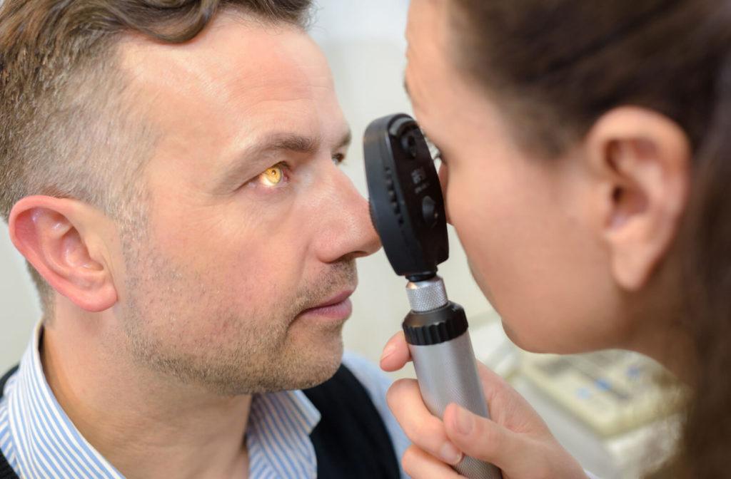 A female ophthalmologist is examining a male patient's eye with the use of a direct ophthalmoscope.