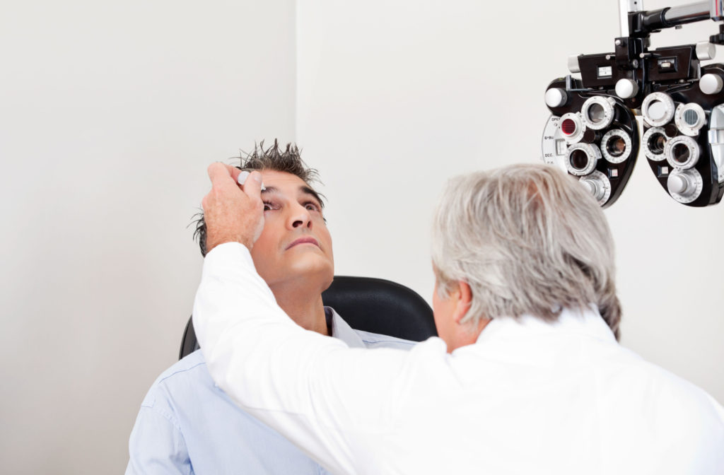 An optometrist applying artificial tears to his patient's right eye.