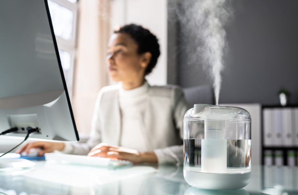 A professional-looking woman working in an office with a humidifier.